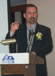Ron Adams speaking at a podium.