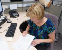 An employee shuffling through paperwork at her desk. 